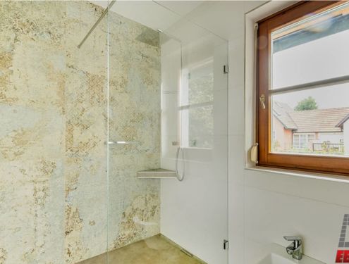 Badezimmer mit Dekorfliese im Großformat und schlichtem Waschtisch aus Holz
