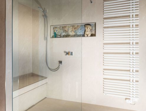 Ein helles und freundliches Badezimmer mit Waschtisch aus Holz und Duschbank mit indirekter Beleuchtung
