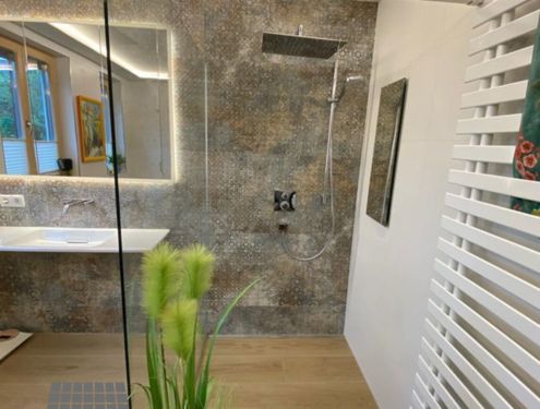 Ein extravagantes Badezimmer mit Dekor- und Holzoptikfliesen.
