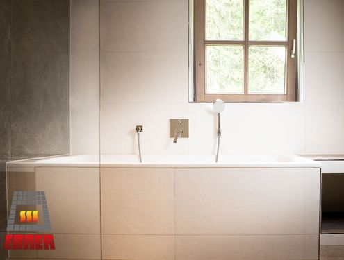 Modern, zeitlos und im Landhausstil. Durch die schlichten Fliesenfarben und den Badezimmermöbeln aus Holz wirkt das Badezimmer gemütlich und freundlich.