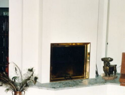Ein schlichter Heizkamin mit durchgezogener Ofenbank und großem Sichtfenster