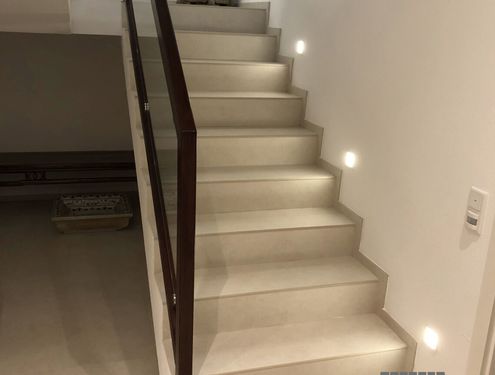 Diese Treppe wurde passend zum Badezimmer der Familie verfliest. Als Beleuchtung dienen Wandspots, die die Treppe noch besser hervorheben.