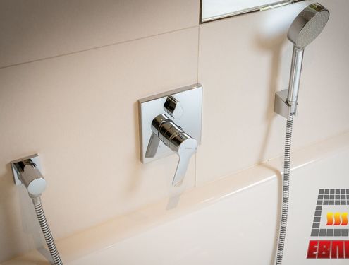 Modern, zeitlos und im Landhausstil. Durch die schlichten Fliesenfarben und den Badezimmermöbeln aus Holz wirkt das Badezimmer gemütlich und freundlich.
